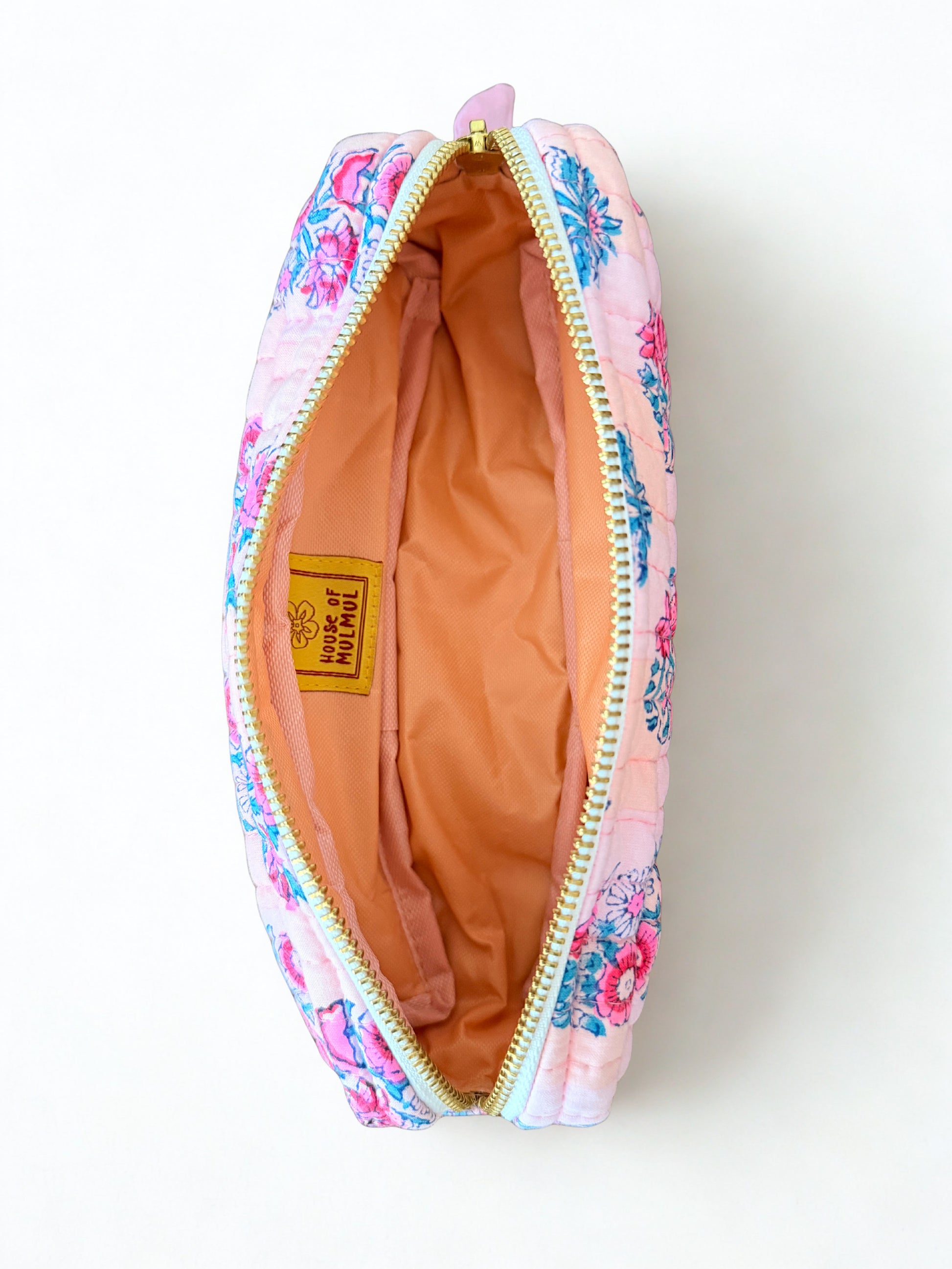 House of Mulmul - Cotton Quilted Makeup Barrel Pouch. A pink quilted cosmetic pouch with a colorful floral print, shown open to reveal a peach-colored interior lining and a yellow 'Peach All Natural' brand label.