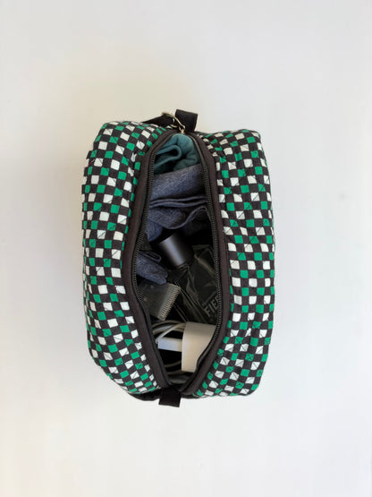 House of Mulmul - Handblock Printed Travel Makeup Quilted Pouch set. A woven zippered toiletry bag with a green, black, and white checkered pattern, shown open with folded toiletries inside against a plain white background.
