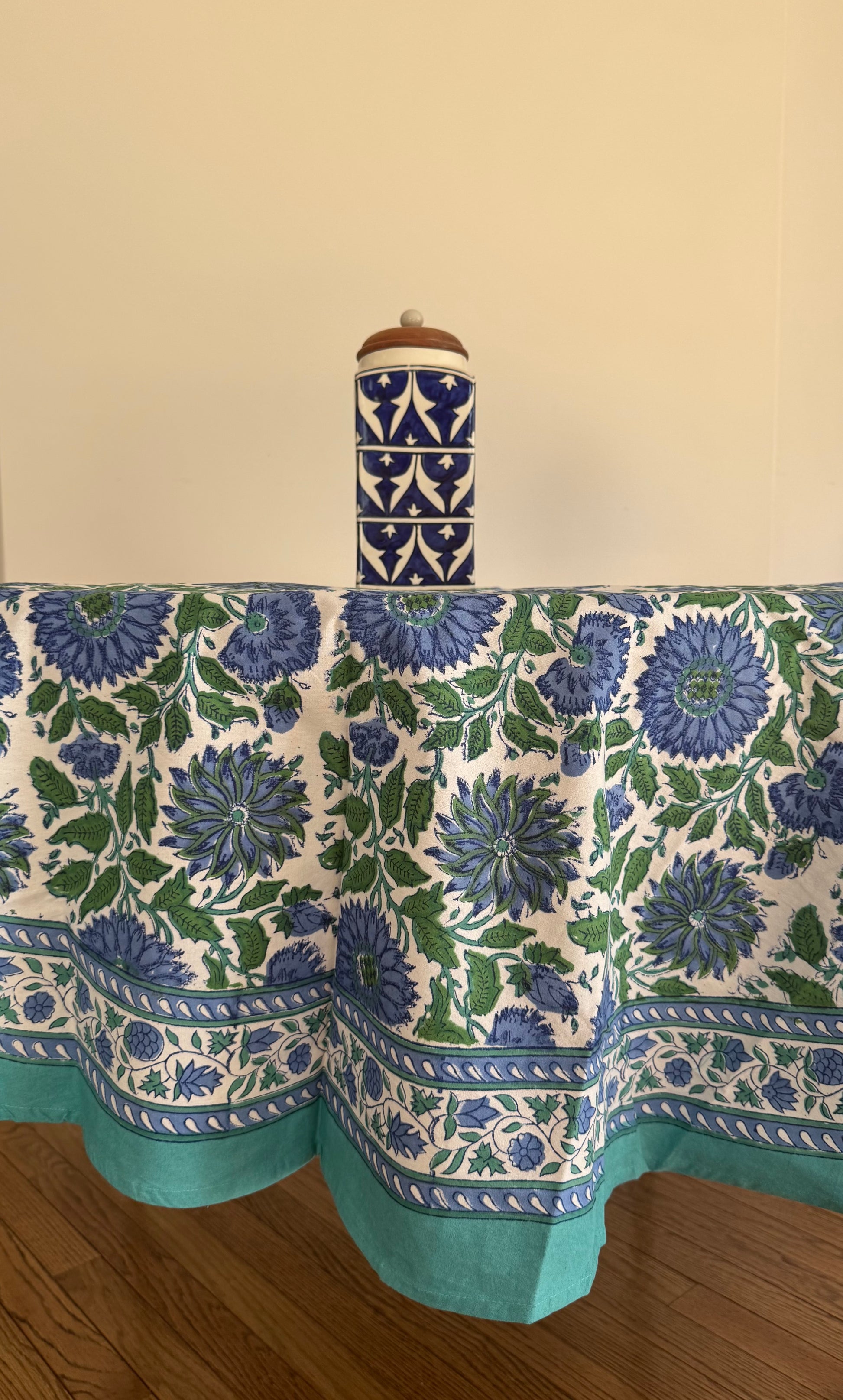 House of Mulmul - Cotton Table Cloth Round. Tablecloth with blue floral pattern on a wooden surface