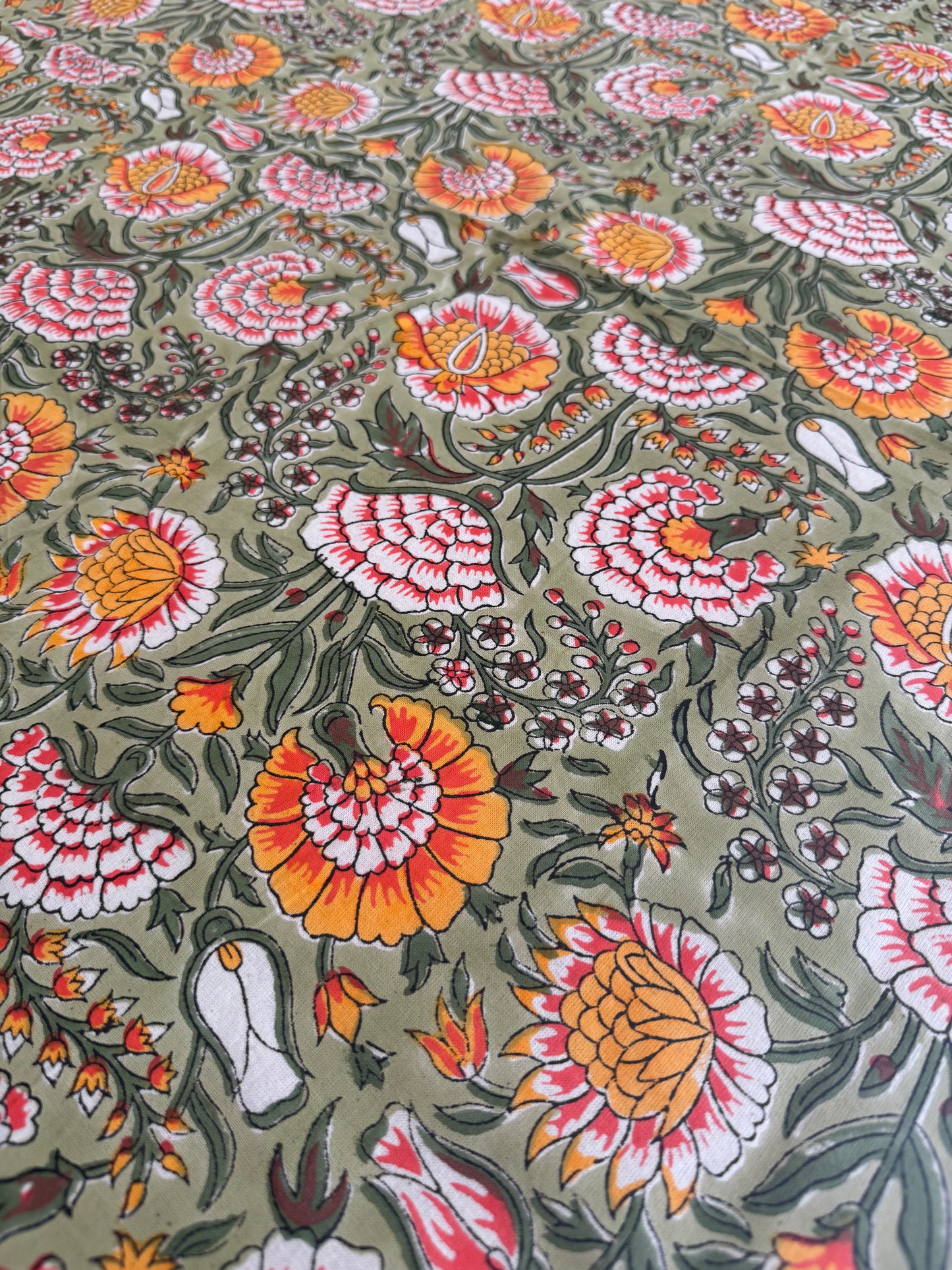 House of Mulmul - Cotton Table Cloth Round. Floral pattern with orange, pink, and white flowers on a green background