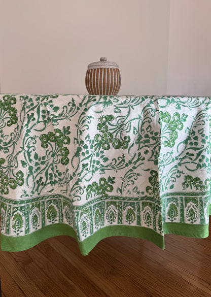 House of Mulmul - Cotton Table Cloth Round. Green and white patterned tablecloth on a wooden table with a neutral background
