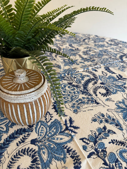 House of Mulmul - Cotton Table Cloth Round. Decorative fabric with blue floral pattern, green plant, and decorative box.
