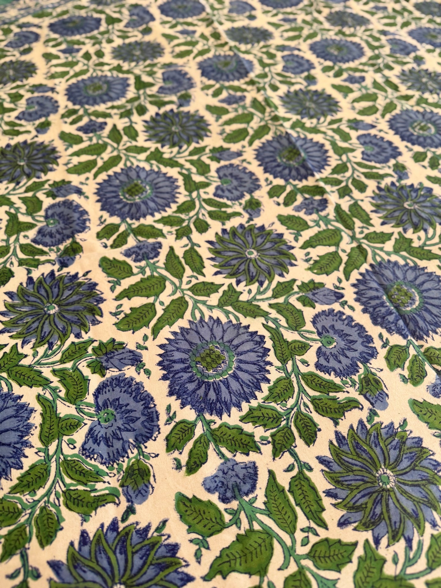 House of Mulmul - Cotton Table Cloth Round. Patterned fabric with blue and green flowers on a beige background