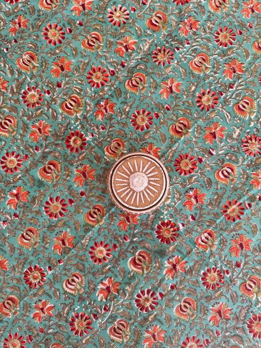 House of Mulmul - Cotton Table Cloth Round. Decorative fabric pattern with flowers and a central sun design on a teal background