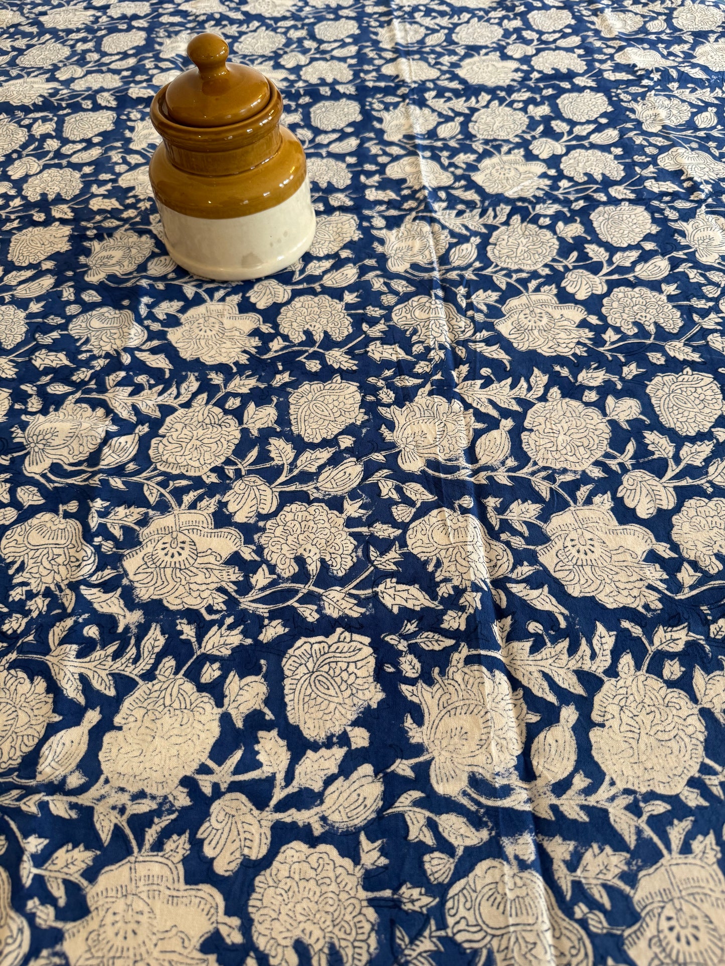 House of Mulmul - Cotton Table Cloth Round. Close-up of a blue fabric with white floral pattern and a wooden knob.