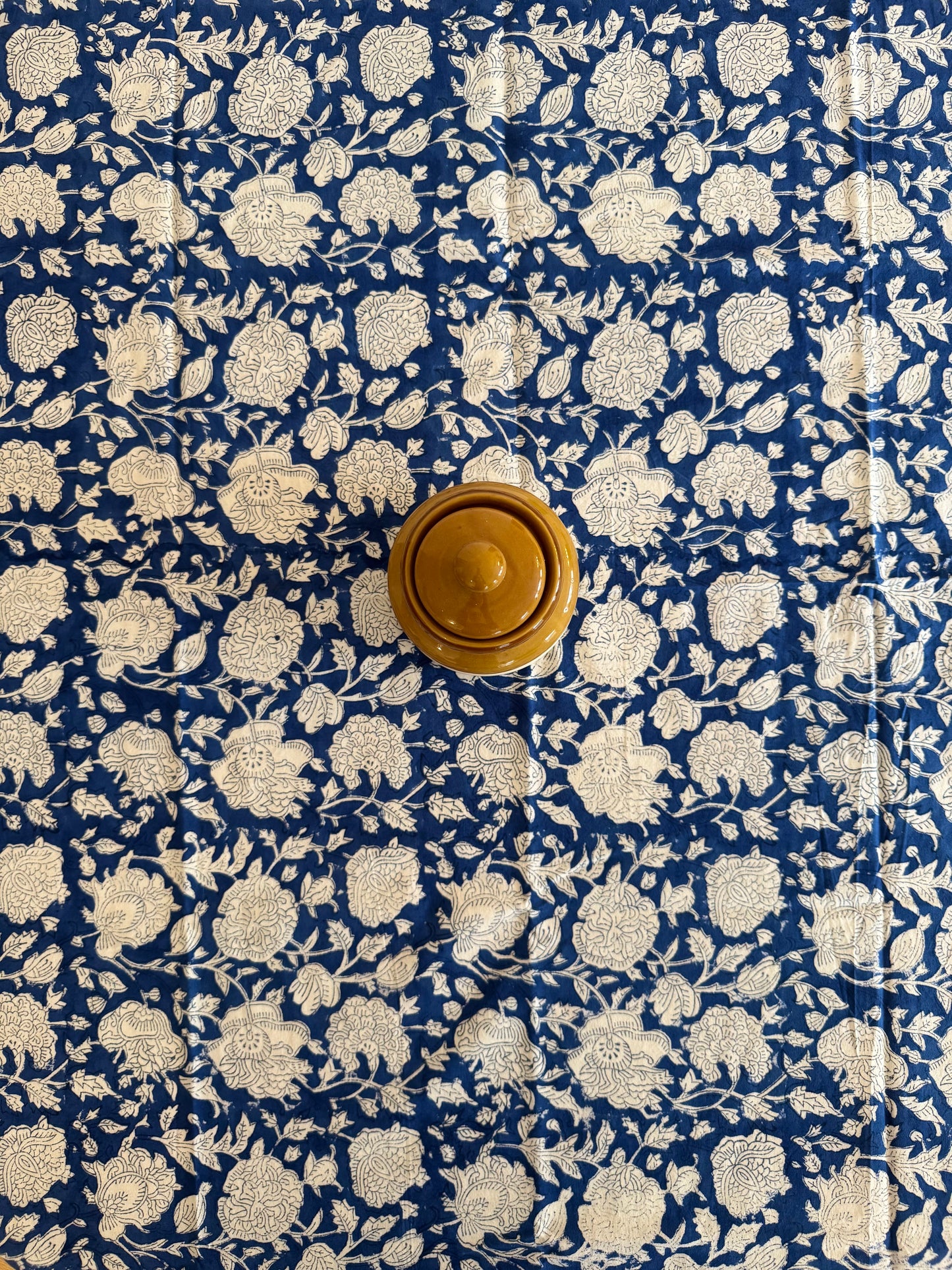 House of Mulmul - Cotton Table Cloth Round. Floral patterned fabric with a wooden knob on a blue background