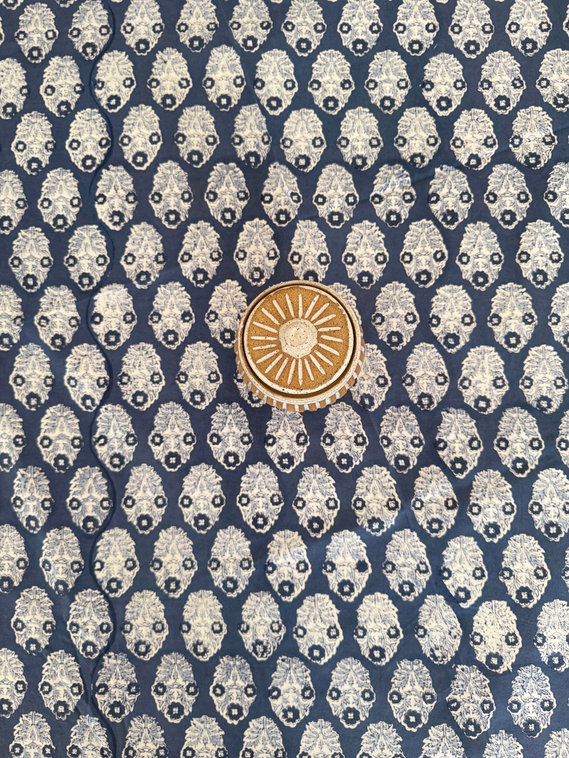 House of Mulmul - Cotton Table Cloth Round. Patterned fabric with a central gold emblem on a blue background