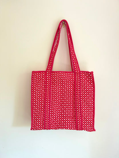 House of Mulmul - Cotton Tote Bags. A red fabric tote bag with white polka dots and long shoulder straps, hanging against a plain off-white wall.