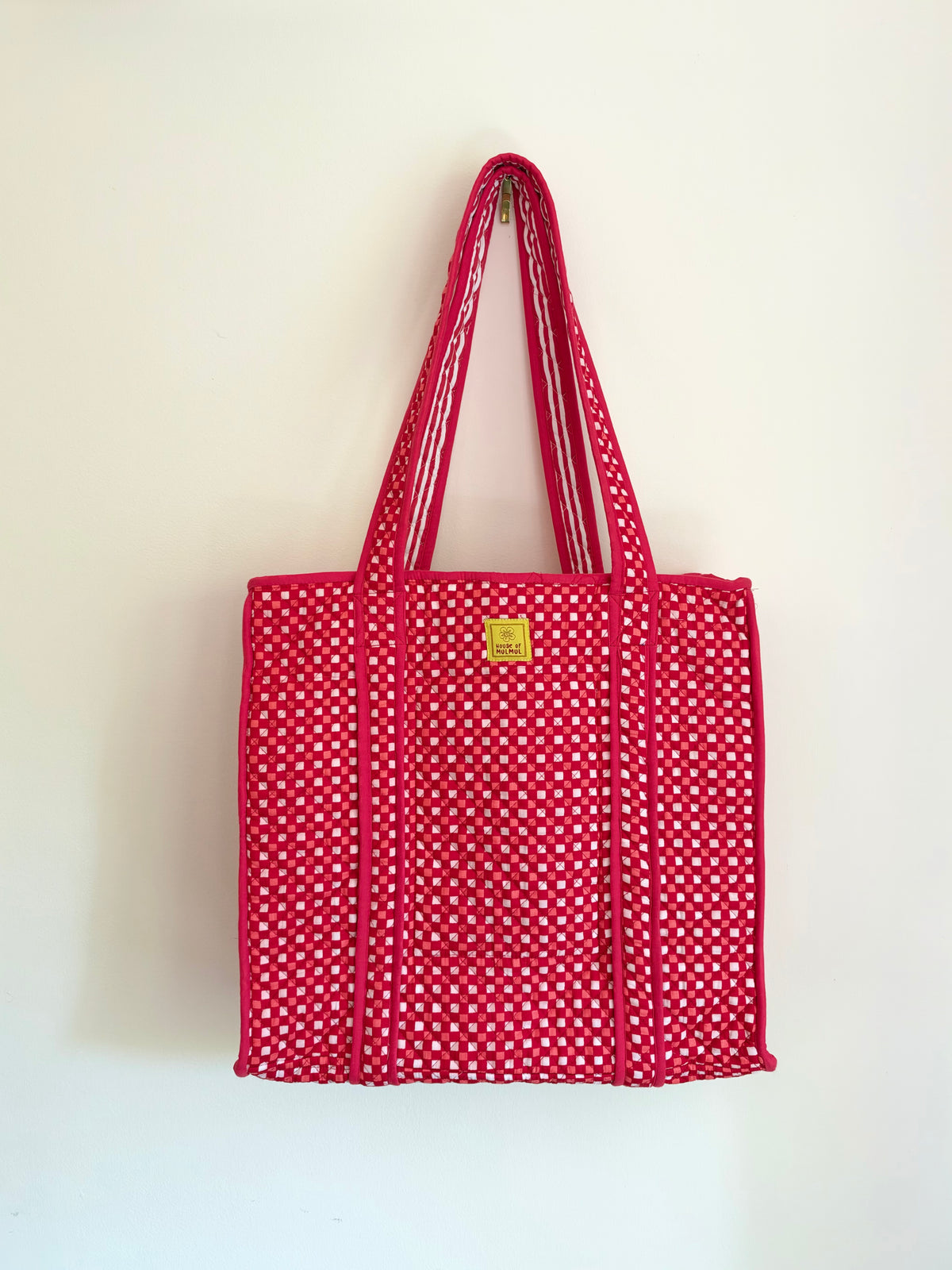 House of Mulmul - Cotton Tote Bags. A red woven tote bag with white polka dots and dual shoulder straps, hanging against a plain off-white wall.
