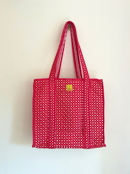 House of Mulmul - Cotton Tote Bags. A red woven tote bag with white polka dots and dual shoulder straps, hanging against a plain off-white wall.