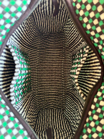 House of Mulmul - Cotton Tote Bags. Close-up view from inside a woven tote bag, showing a black and beige striped fabric lining with a dark brown trim, surrounded by a green and beige checkered woven pattern.