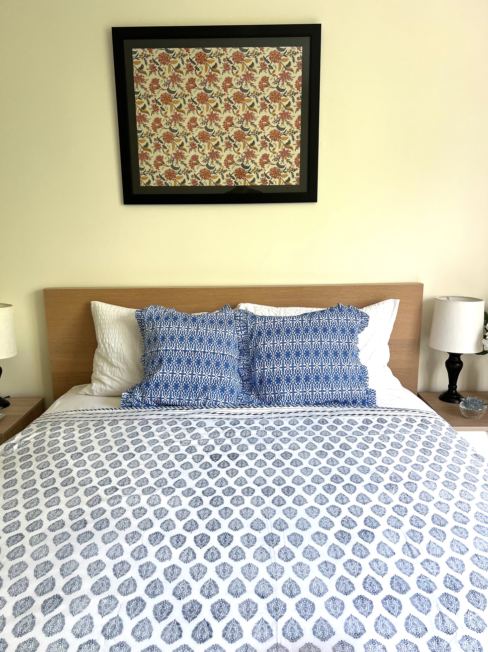 House of Mulmul - Cotton Coverlets (Dohar). Bedroom with blue and white patterned bedding, pillows, and a framed artwork on the wall.