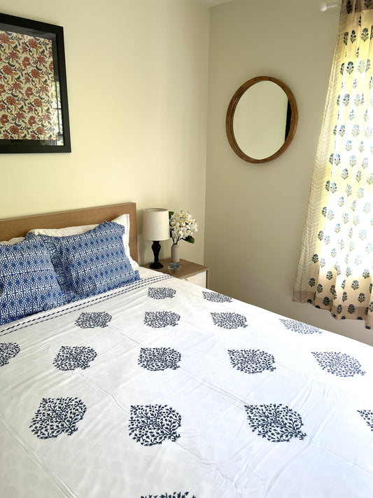 House of Mulmul - Cotton Coverlets (Dohar). Bedroom with floral bedspread, pillows, and decor elements.