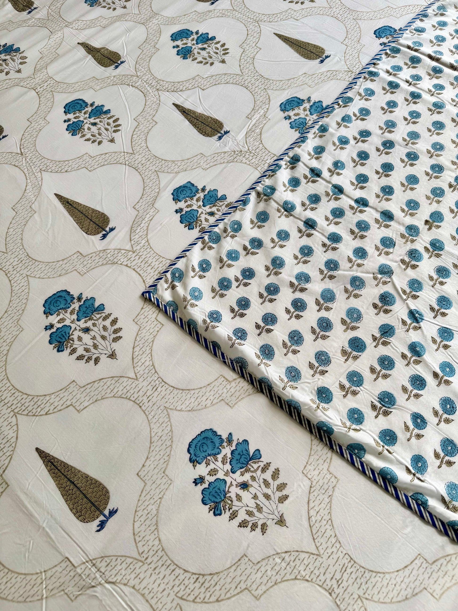 House of Mulmul - Coverlet Dohar blanket. Bedroom with reversible cotton coverlet blanket. Muslin dohar with palms cypress leaf and blue and brown colors, white background.