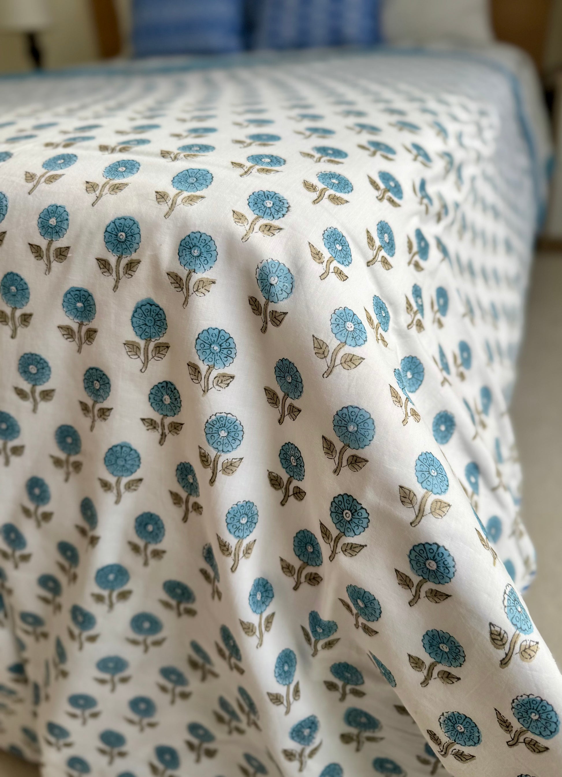 House of Mulmul - Coverlet Dohar blanket. Bedroom with reversible cotton coverlet blanket. Muslin dohar with palms cypress leaf and blue and brown colors, white background.