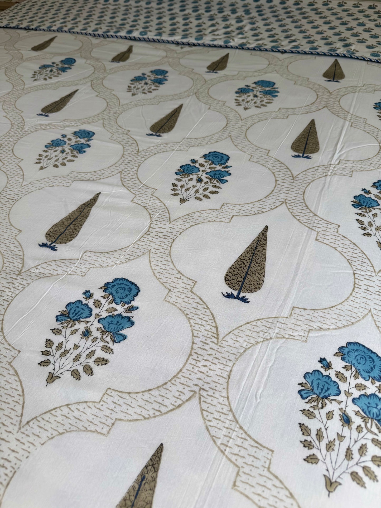 House of Mulmul - Coverlet Dohar blanket. Bedroom with reversible cotton coverlet blanket. Muslin dohar with palms cypress leaf and blue and brown colors, white background.