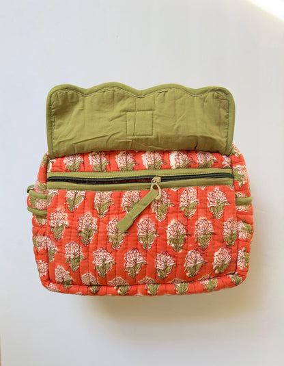 House of Mulmul - Handblock Printed Travel Makeup Quilted Pouch setA quilted cosmetic bag with a coral orange and green floral block print exterior, olive green interior lining, and a matching olive green zipper pull, shown against a plain white background.