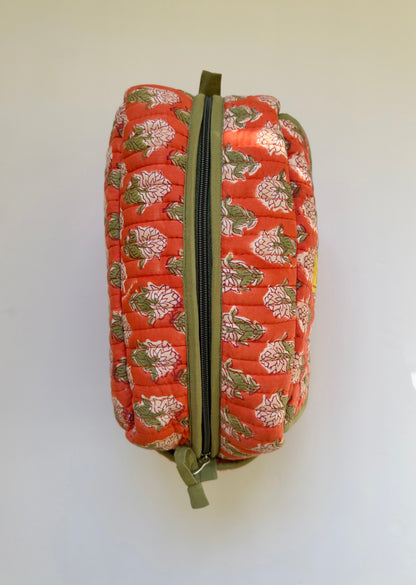House of Mulmul - Handblock Printed Travel Makeup Quilted Pouch setA quilted cosmetic pouch with a vibrant orange-red background and a green, white, and pink floral pattern, featuring a green zipper.