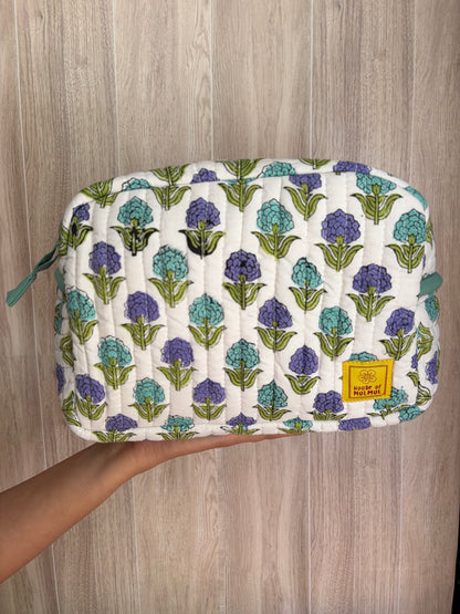 House of Mulmul - Quilted Blockprint Travel Makeup pouch. White Lavender Green Floral patterned makeup bag held by a hand on a wooden surface.