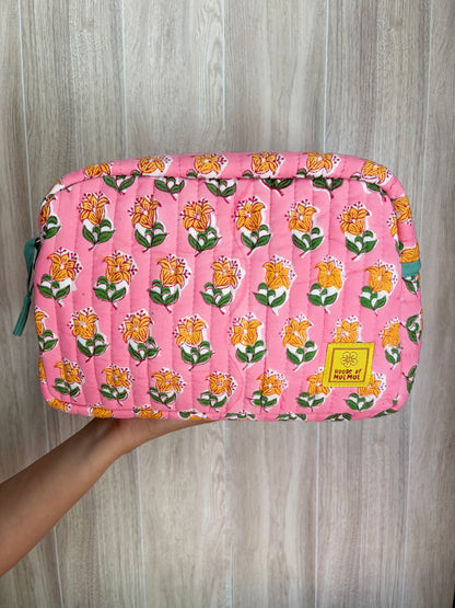House of Mulmul - Quilted Blockprint Travel Makeup pouch. Pink Orange Green Floral patterned makeup bag held by a hand on a wooden surface.