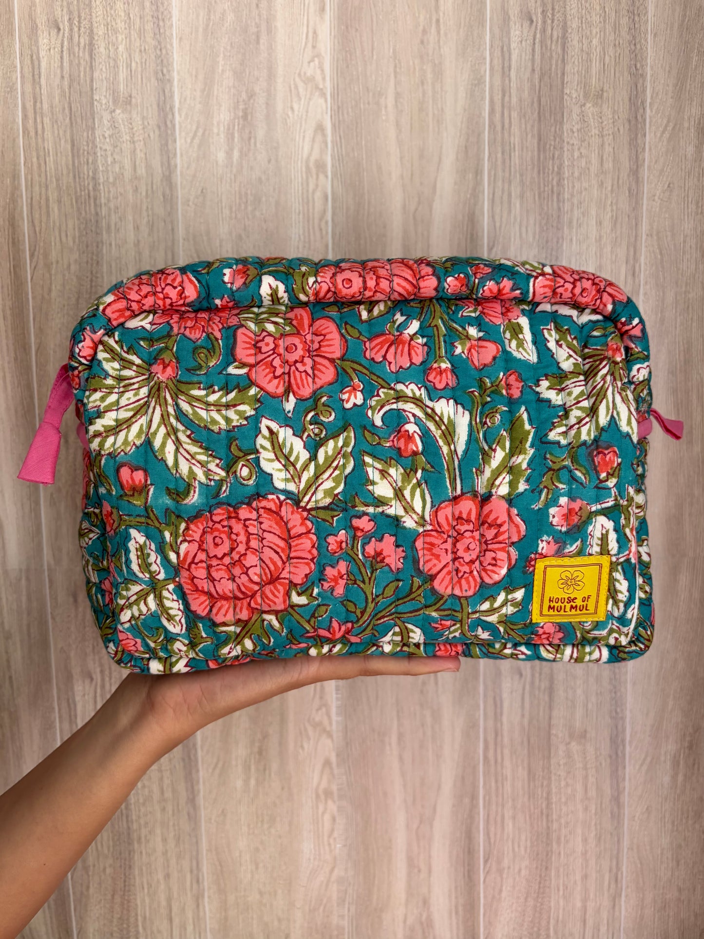 House of Mulmul - Quilted Blockprint Travel Makeup pouch. Green Pink Jade Floral patterned makeup bag held by a hand on a wooden surface.