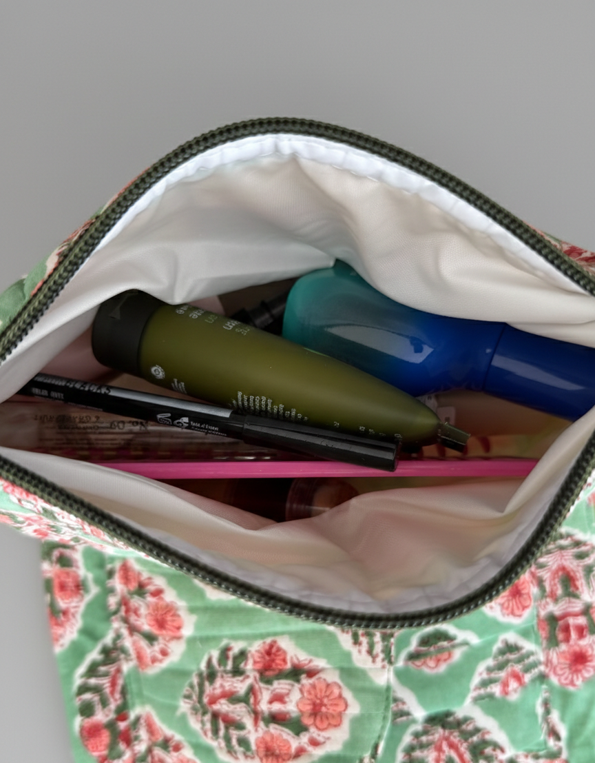 House of Mulmul - Quilted Foldable Travel Makeup pouch. Floral-patterned pouch with stationery toiletry items on a gray background