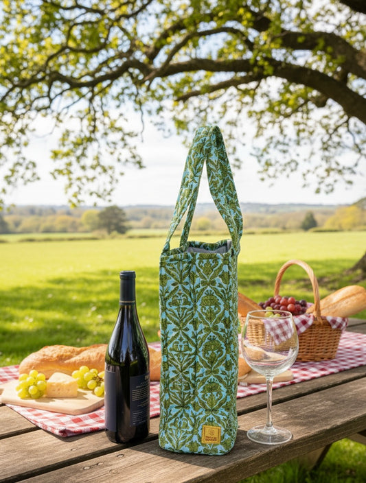 House of Mulmul - Quilted Wine Tote Bag. Wine bottle in a green patterned wine bag on a picnic table with a scenic background