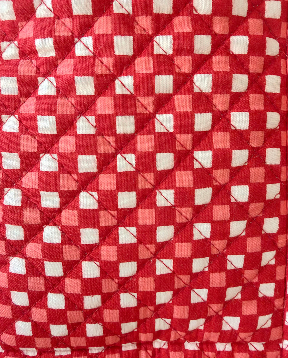 House of Mulmul - Quilted Wine Tote Bag. A close-up of a quilted fabric with a red and white gingham checkered pattern, stitched diagonally to form diamond quilting.