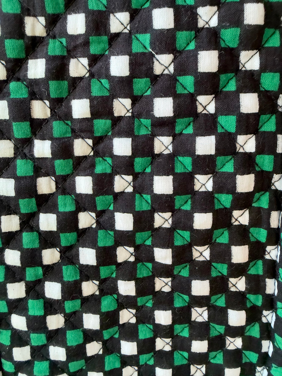 House of Mulmul - Quilted Cotton Bag. A close-up of a quilted fabric with a repeating geometric pattern of green, black, and off-white squares.