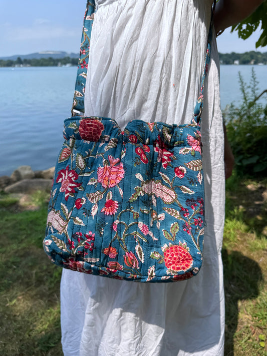House of Mulmul - Garden Wayfarer Bucket Bag, Cotton bag, Crossbody sling bag. Floral-patterned fabric held by a person outdoors.