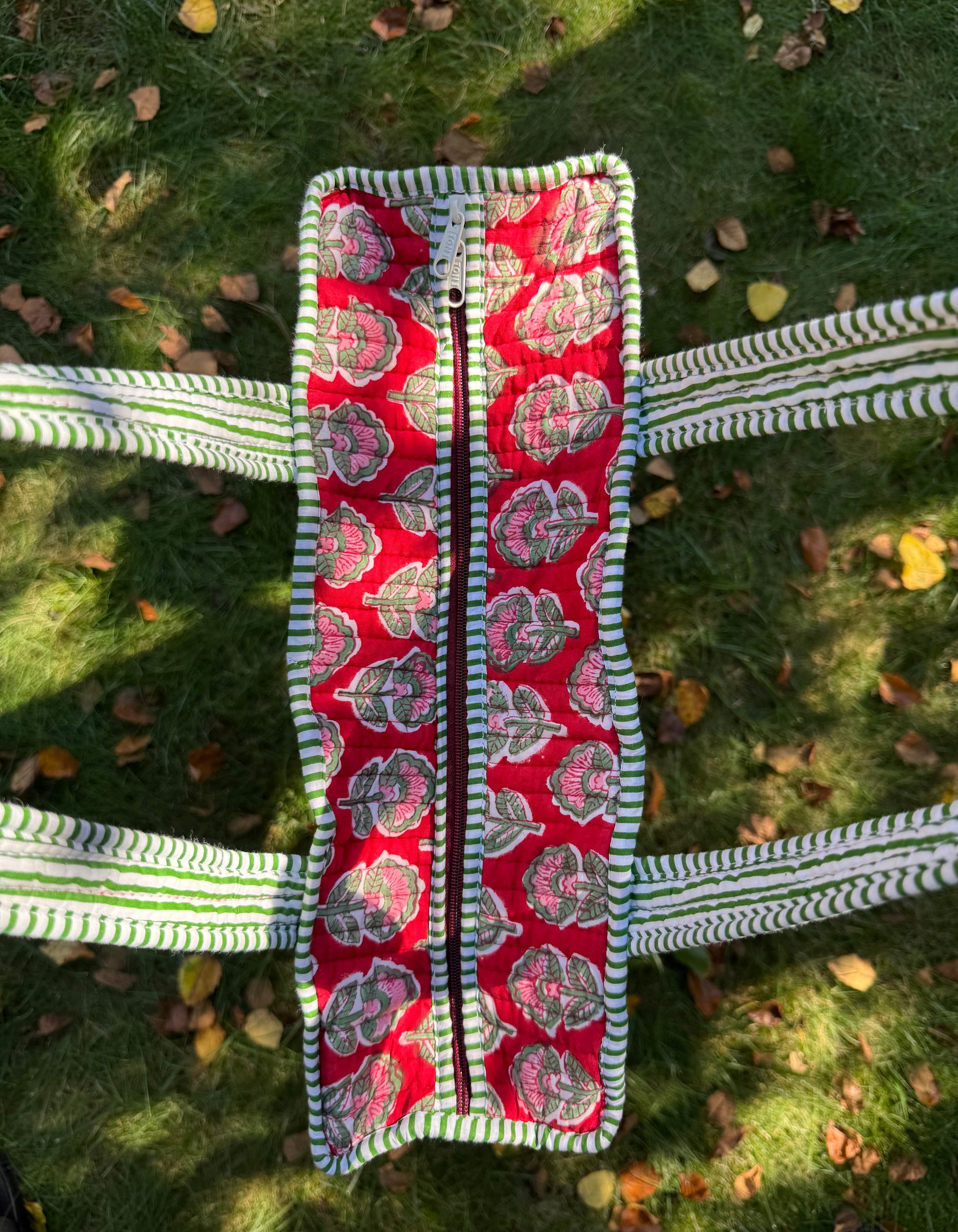 House of Mulmul - Cotton Tote Bag. Red patterned bag with a zipper on a grassy background