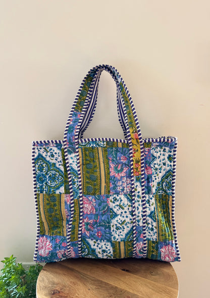 House of Mulmul - Cotton Tote Bag, Travel Bag. Multicolored patchwork tote bag with floral patterns on a wooden surface.