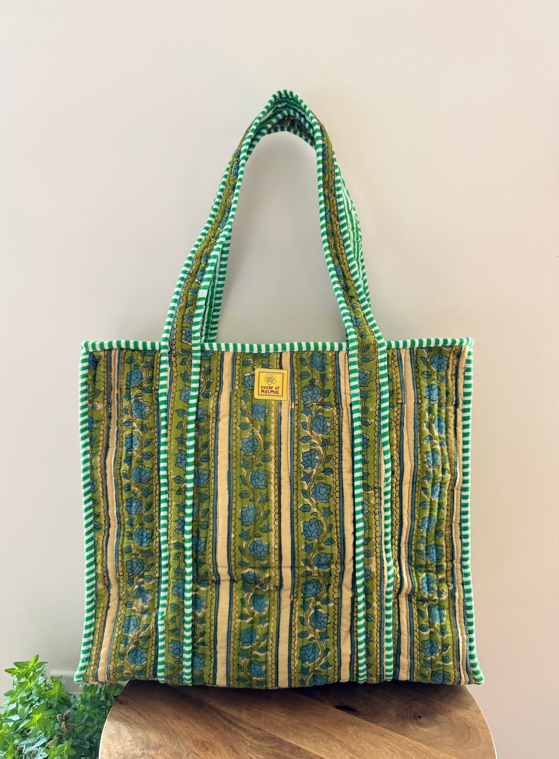 House of Mulmul - Cotton Tote Bag, Travel Bag. Green and brown patterned tote bag on a wooden surface with a light background