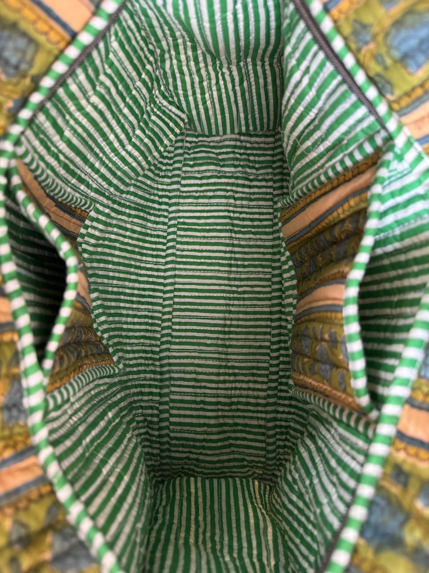 House of Mulmul - Cotton Tote Bag, Travel Bag. Close-up of a green and white striped fabric interior with pockets and a colorful patterned background.