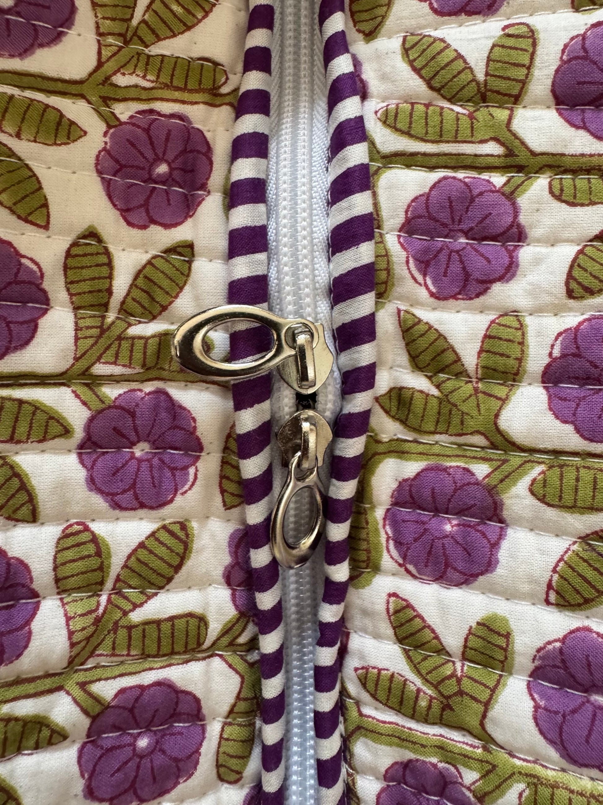 House of Mulmul - Cotton Tote Bag, Travel Bag. Close-up of a purple and white striped zipper on a floral-patterned fabric background