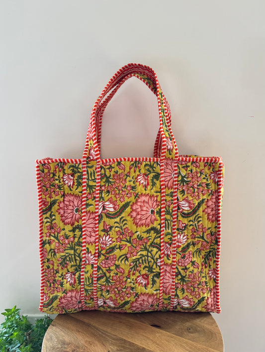 House of Mulmul - Cotton Tote Bag, Travel Bag. Floral patterned tote bag with red accents on a wooden stool against a light background