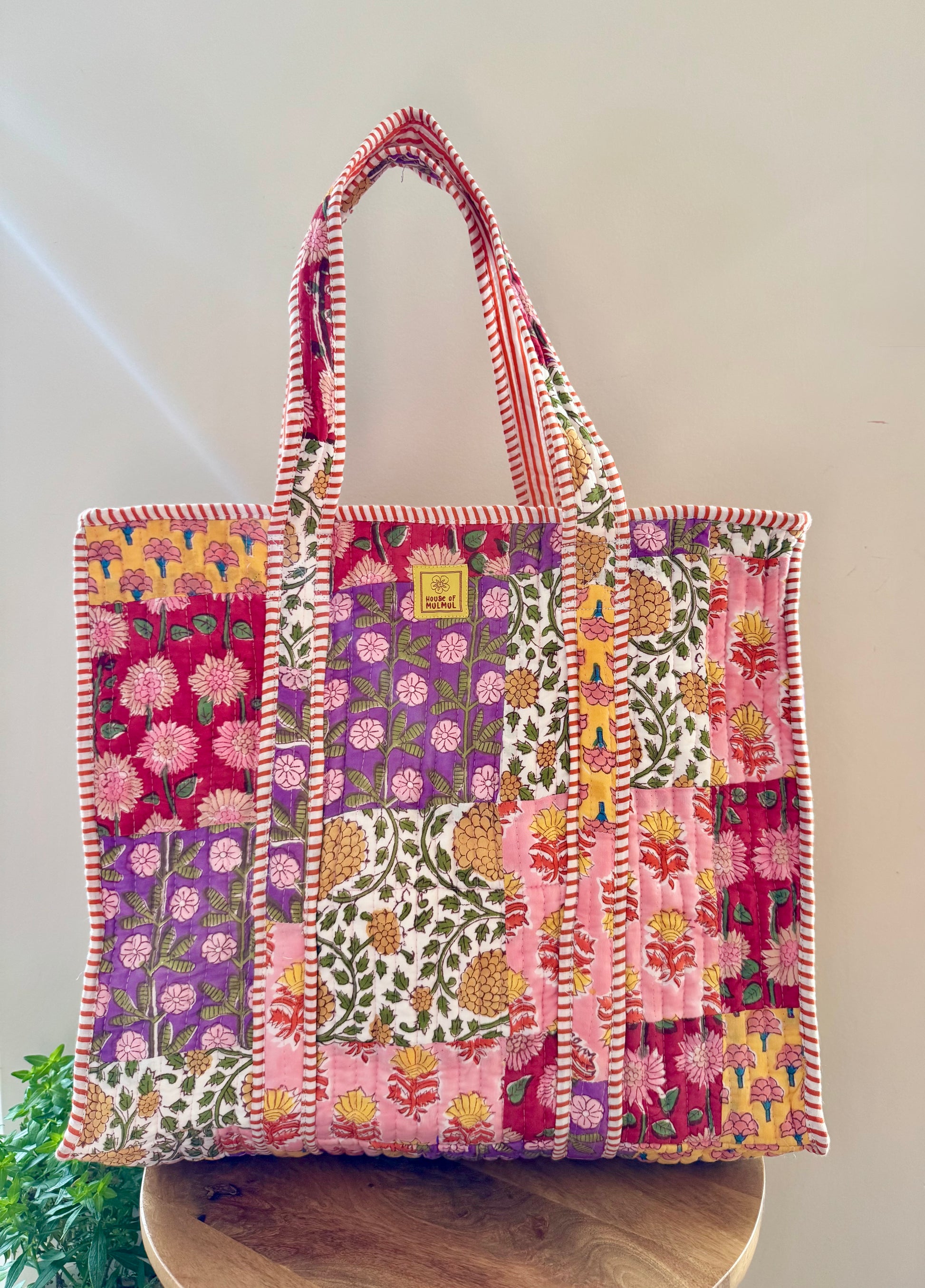 House of Mulmul - Cotton Tote Bag, Travel Bag. Colorful patchwork tote bag on a wooden surface with a white background