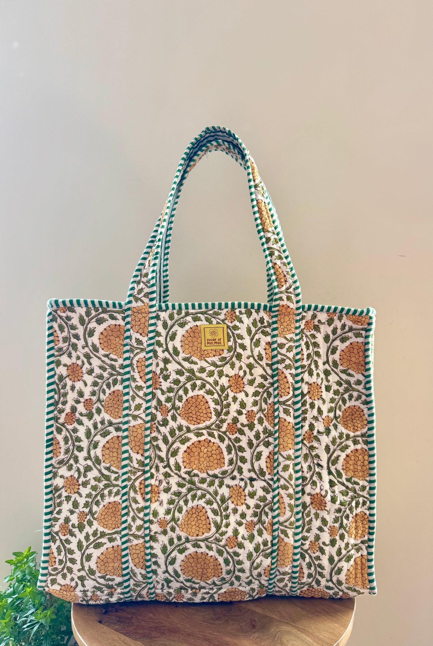 House of Mulmul - Cotton Tote Bag, Travel Bag. Floral patterned tote bag on a wooden surface with a plain background